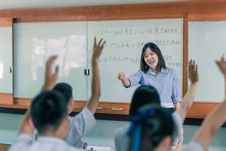 日本語の授業で挙手する生徒たちと教師