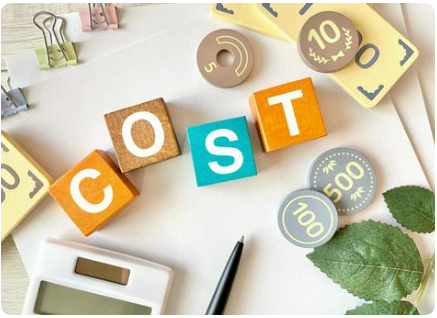 「COST」と書かれた積み木、電卓、ペン、硬貨に見立てた木製コインなどが写っている。費用の検討や経費を象徴する画像。